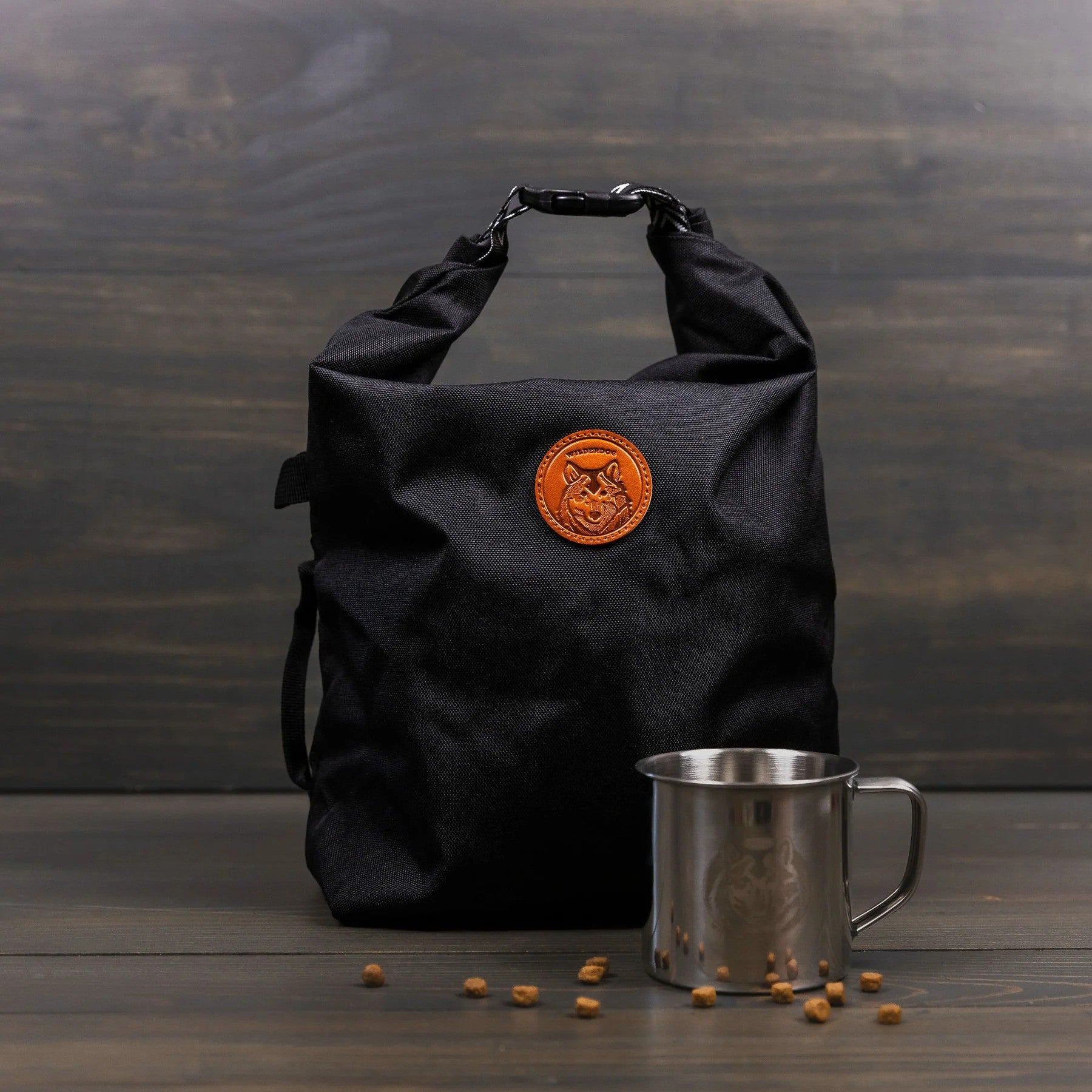 Black dog food travel bag with roll-top closure and orange logo