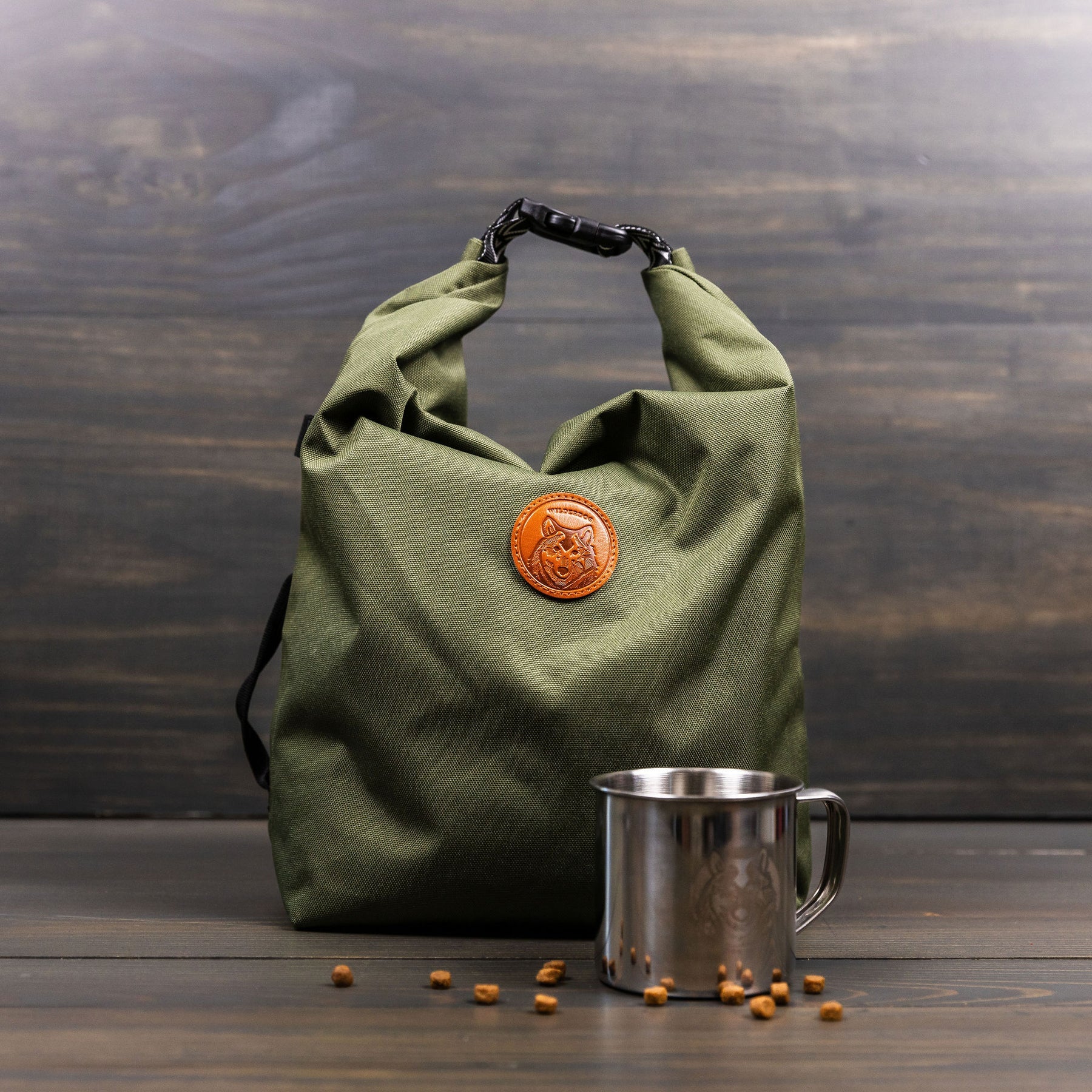 Olive green roll-top dog kibble bag with black chevron strap and orange logo
